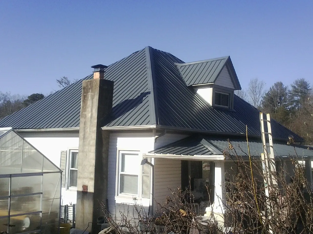 Dark blue standing seam metal roof on a white farmhouse with dormer — Slate & Tile Roof Repair by Roofing Brothers in Fish Haven