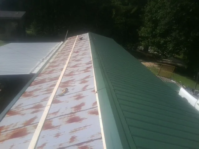 Old rusted panels beside newly installed green metal roofing — Wind Damage Roof Repair by Roofing Brothers in Fish Haven