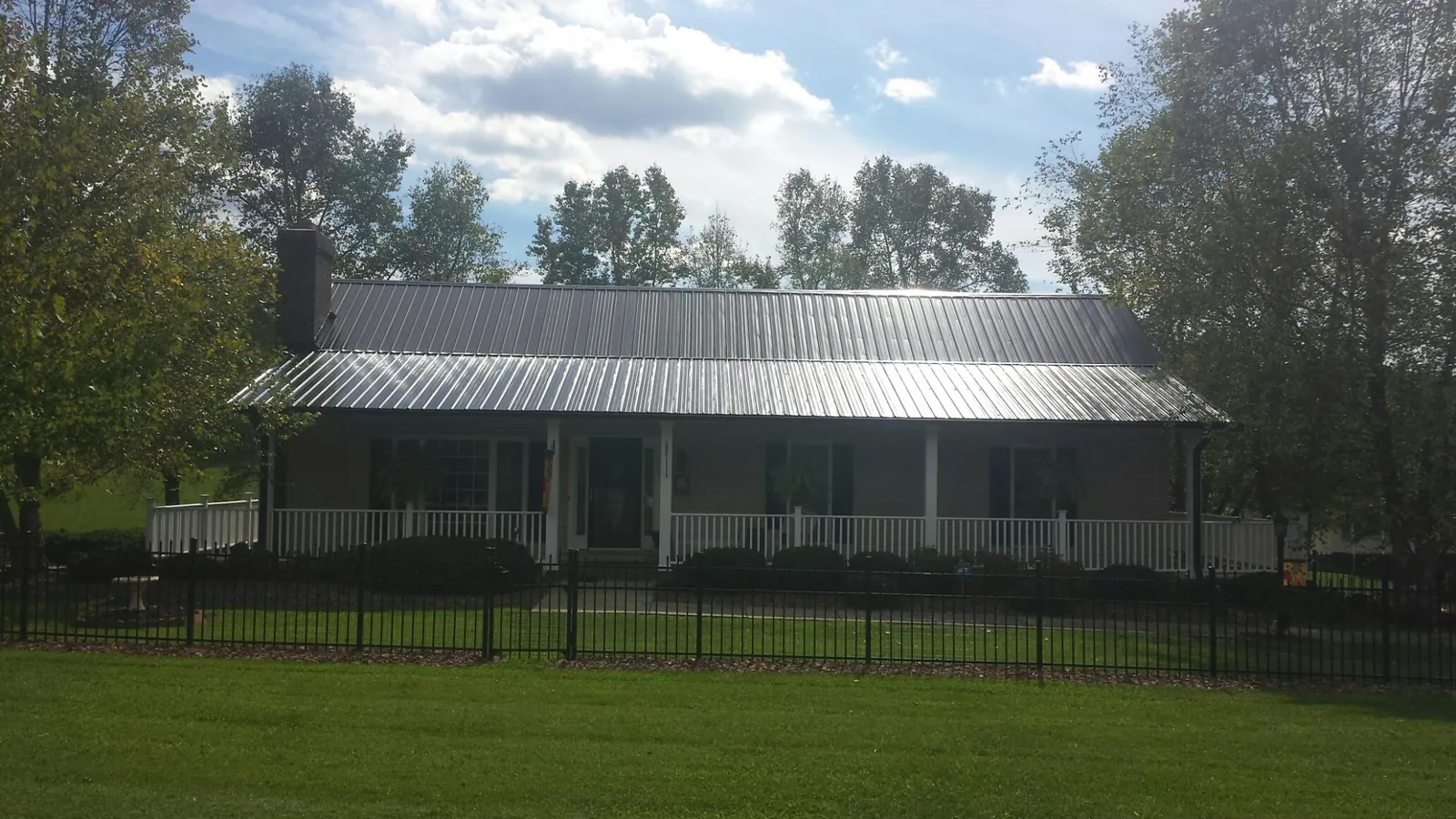 Gray metal roof on a brick ranch with a full width front porch — Gutter Guard Installation work by our crew in Fish Haven