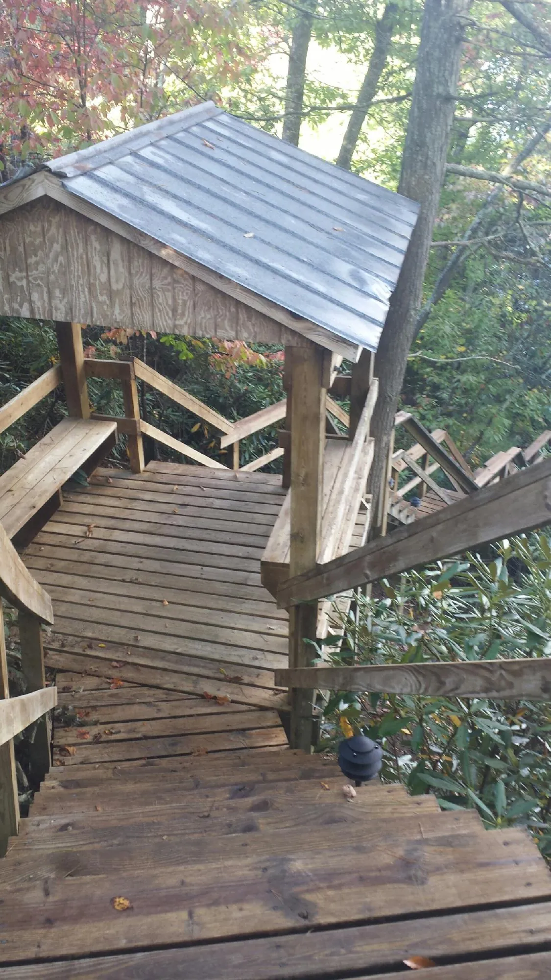 Metal roofed shelter over wooden steps on a wooded walkway — Skylight Repair & Installation work by our crew in Fish Haven